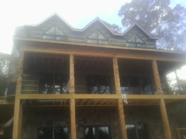 Dormers and porch framing on a large log home under construction — Roof Coating work by our crew in Millville