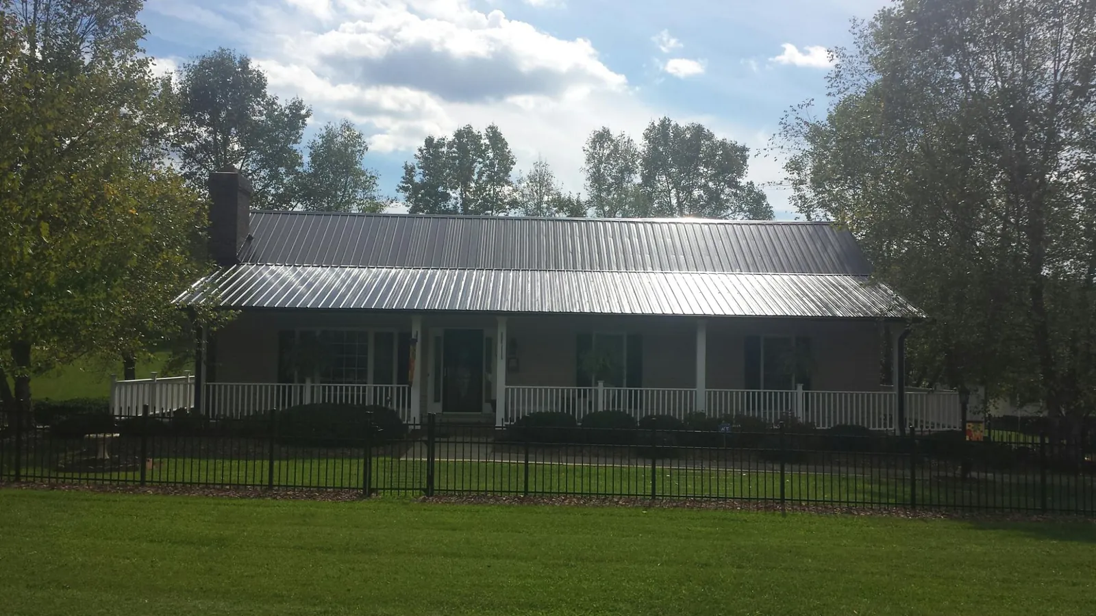 Gray metal roof on a brick ranch with a full width front porch — Gutter Guard Installation work by our crew in Millville